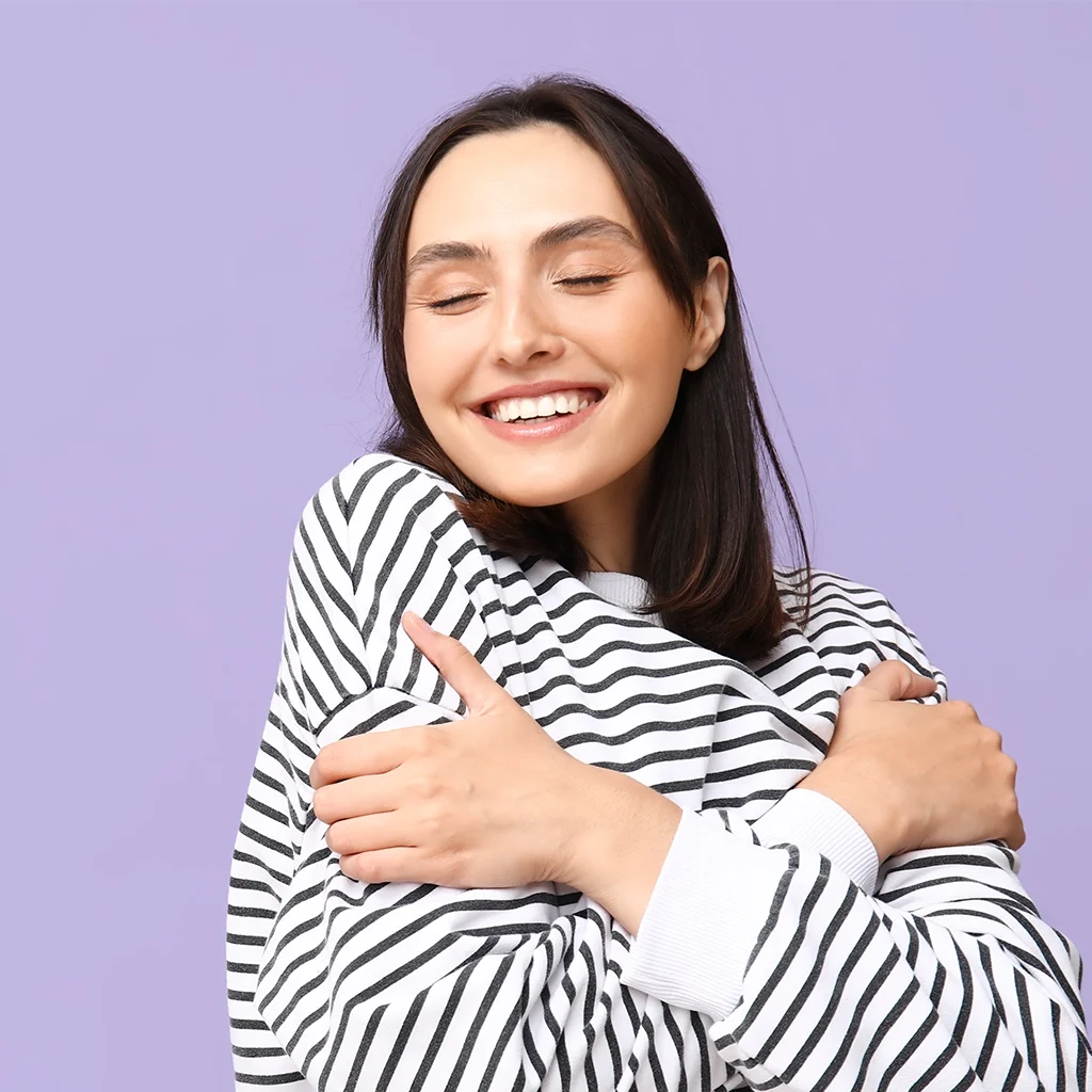 cute young girl giving herself a hug and smiling