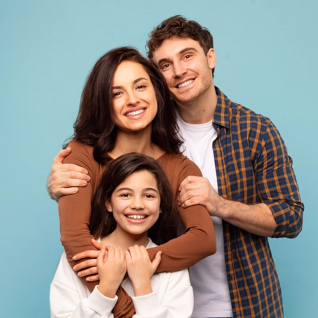 portrait of young dad and mom embracing their daughter